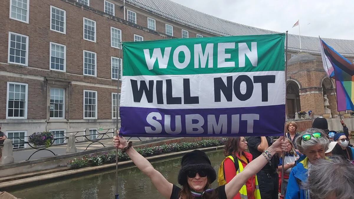 A woman holding a "Women will not submit" banner in Bristol, England, on June 19, 2022. (Courtesy of Standing For Women)