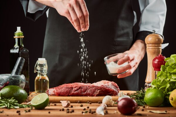 man seasoning steak with salt