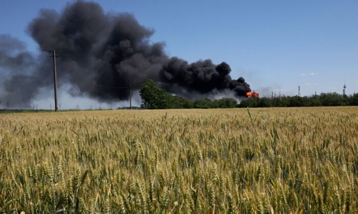 A fire from a gas processing plant continues to burn behind a field of wheat after the plant was hit by shelling a few days prior in Andriivka in the Kharkiv region in Ukraine, on June 21, 2022. (Leah Millis/Reuters)