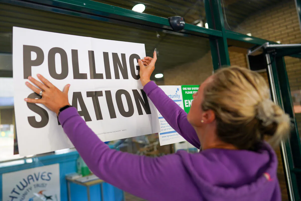 An official attaches a sign to a polling station as voting begins in the by-election in Wakefield, England on June 23, 2022.(Ian Forsyth/Getty Images)