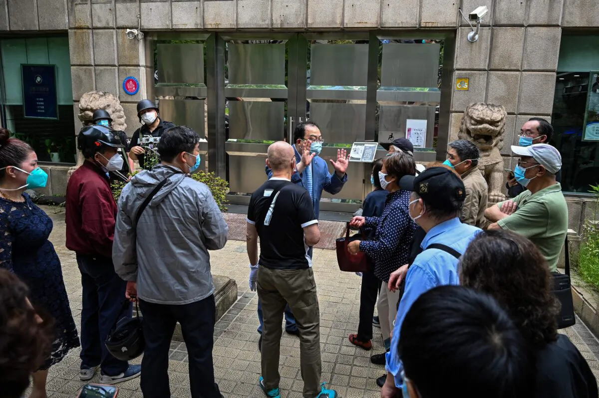A worker talks to people who want to withdraw cash at the entrance of a bank in the Jing'an district of Shanghai on June 1, 2022. (Hector Retamal/AFP via Getty Images)
