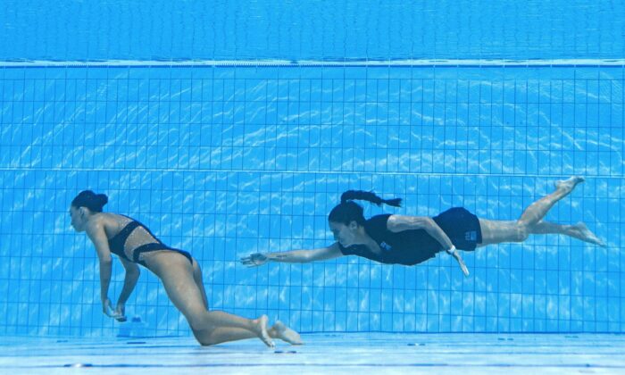 Coach Andrea Fuentes of Team USA (R) swims to recover USA's Anita Alvarez (L) from the bottom of the pool during an incident in the women's solo free artistic swimming finals, during the Budapest 2022 World Aquatics Championships at the Alfred Hajos Swimming Complex in Budapest on June 22, 2022. (Oli Scarff/AFP via Getty Images)