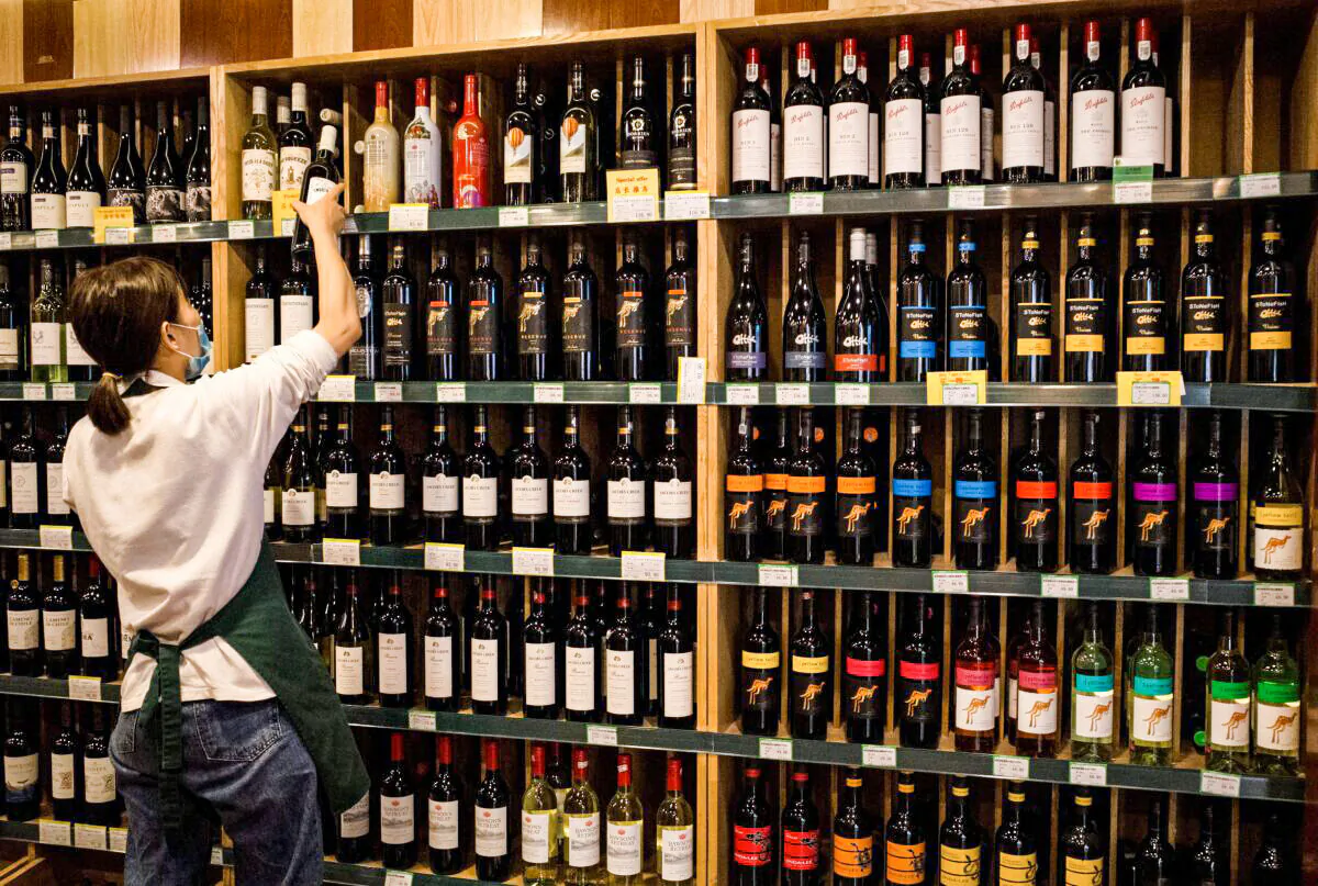 An employee works as Australian-made wine (on display shelves on right) at a store in Beijing on Aug. 18, 2020, the same day that the Chinese regime ramped up tensions with Australia after it launched a probe into wine imports from the country. (Noel Celis/AFP via Getty Images)