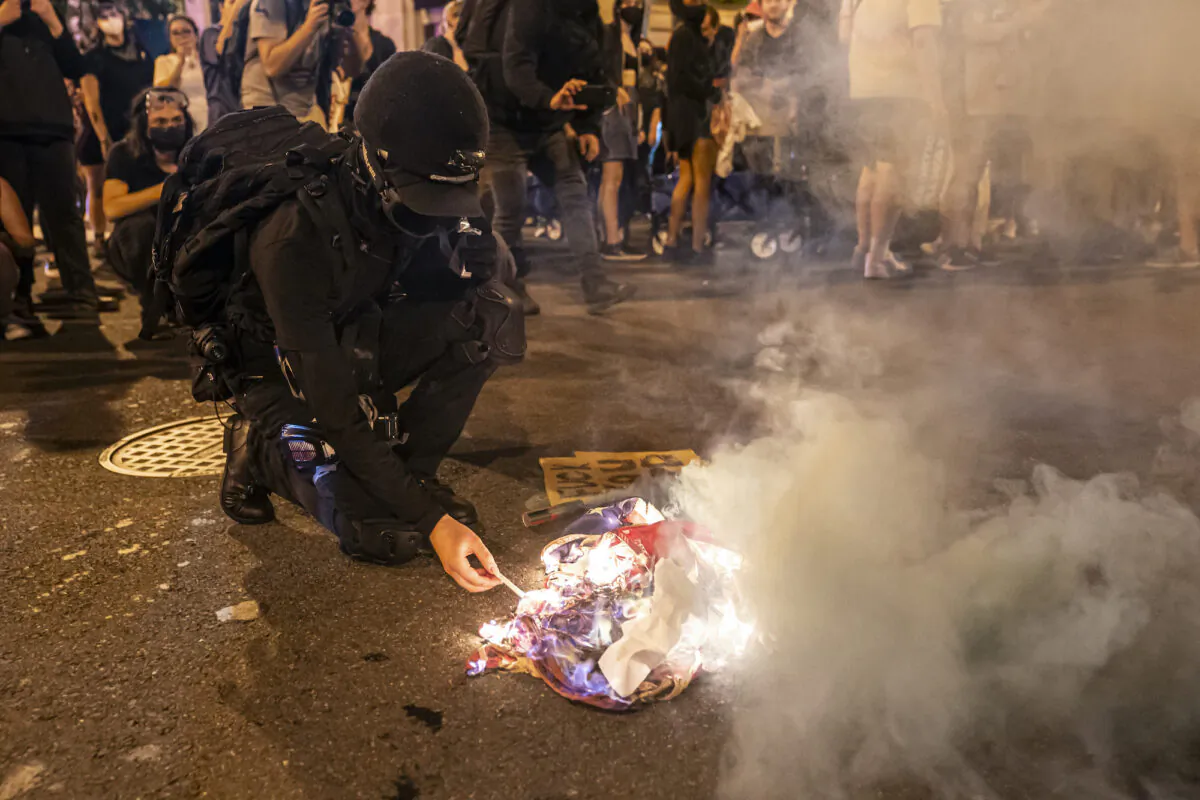 A protester lights a cigarette on a burning American Flag while marching with pro-abortion activists in Washington on June 24, 2022. (Nathan Howard/Getty Images)