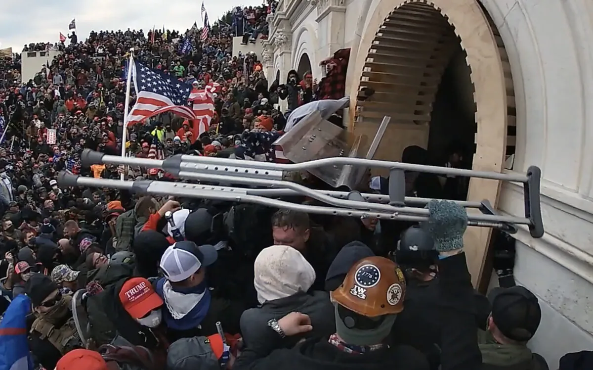 A protester hands off two stolen crutches outside the Lower West Terrace tunnel at the U.S. Capitol on Jan. 6, 2021. (Special to The Epoch Times)