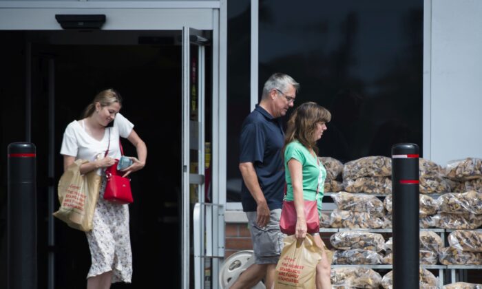 People carrying plastic bags leave a grocery store in Mississauga, Ont., on Aug. 15, 2019. (The Canadian Press/Nathan Denette)