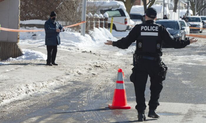A police officer asks a man who wandered into a crime scene, where A 15-year-old girl was killed to leave, in Montreal, February 8, 2021. (The Canadian Press/Ryan Remiorz)