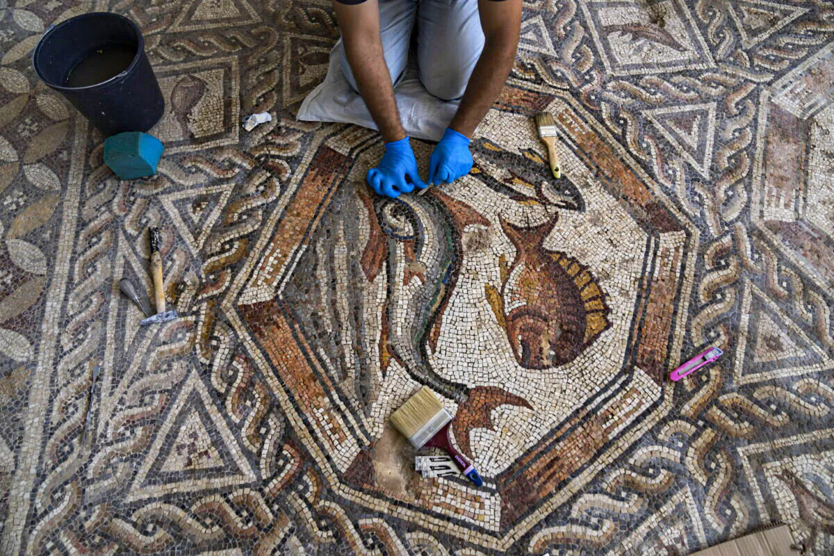 A worker cleans a restored Roman-era mosaic ahead of its display in its hometown ahead of the inauguration of the Shelby White & Leon Levy Lod Mosaic Archaeological Center, in Lod, central Israel, on June 23, 2022. (Oded Balilty/AP Photo)