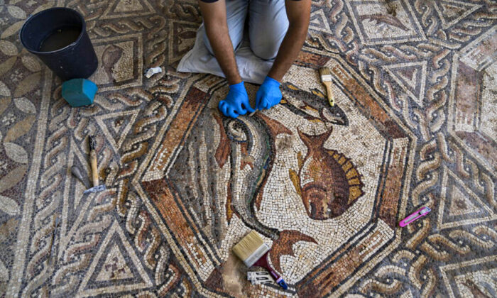 A worker cleans a restored Roman-era mosaic ahead of its display in its hometown ahead of the inauguration of the Shelby White & Leon Levy Lod Mosaic Archaeological Center, in Lod, central Israel, on June 23, 2022. (Oded Balilty/AP Photo)