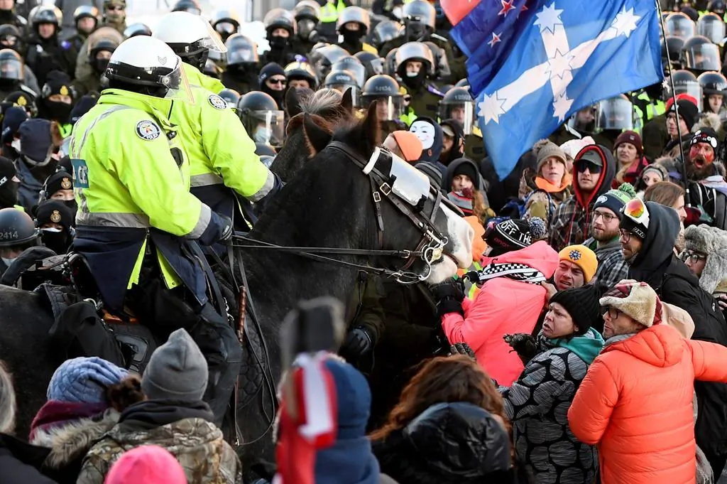 Demonstrators react as mounted police charge to disperse convoy protesters in Ottawa on Feb. 18, 2022. (The Canadian Press/Justin Tang)