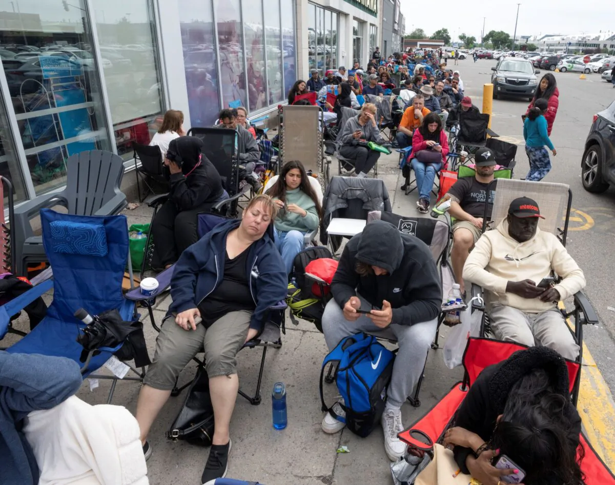 People sit in chairs to ease the long wait outside a passport office in Montreal on June 22, 2022. (The Canadian Press/Ryan Remiorz)