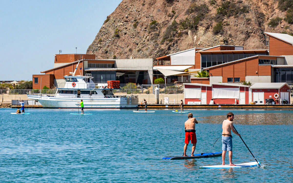 Paddle boarders move in front of the Ocean Institute in Dana Point, Calif., on April 7, 2022. (John Fredricks/The Epoch Times)