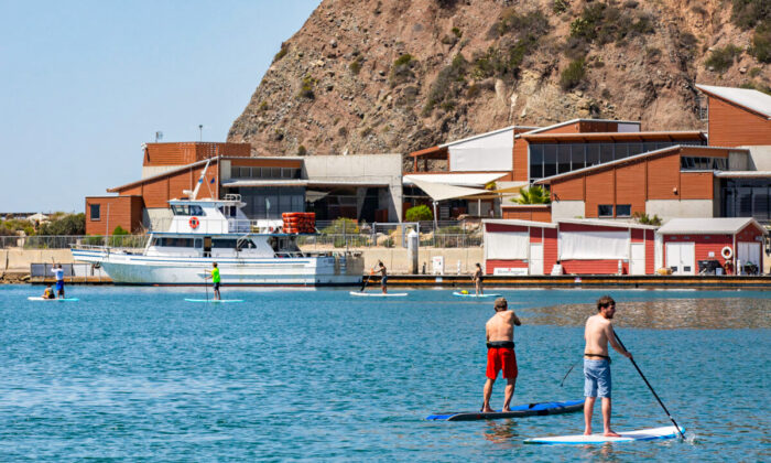 Paddle boarders move in front of the Ocean Institute in Dana Point, Calif., on April 7, 2022. (John Fredricks/The Epoch Times)
