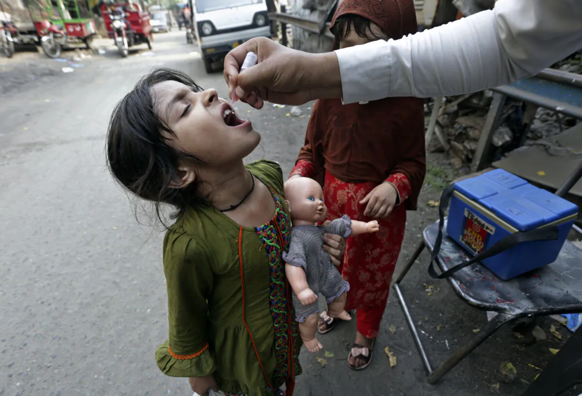 A health worker gives a polio vaccine to a girl on a street in Lahore, Pakistan, on June 27, 2022. Pakistan launched a new anti-polio drive on Monday, with the goal to vaccinate a million children across Pakistan. (K.M. Chaudary/AP Photo)