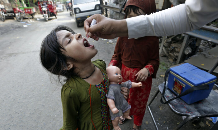 A health worker gives a polio vaccine to a girl on a street in Lahore, Pakistan, on June 27, 2022. Pakistan launched a new anti-polio drive on Monday, with the goal to vaccinate a million children across Pakistan. (K.M. Chaudary/AP Photo)