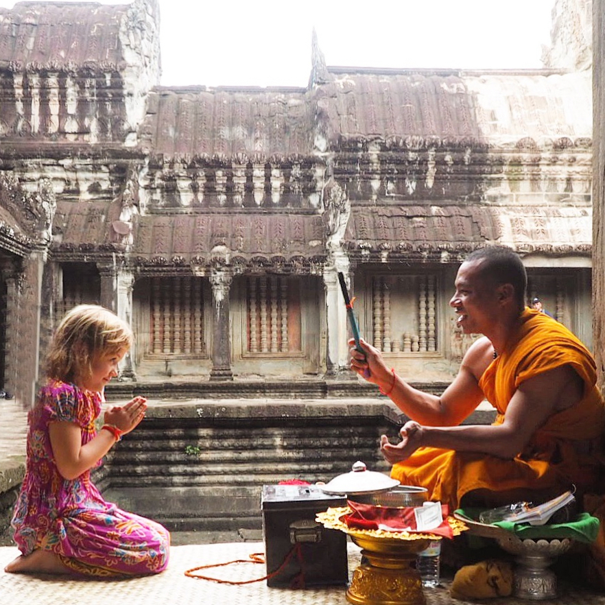 a young girl interacting with a monk at a temple