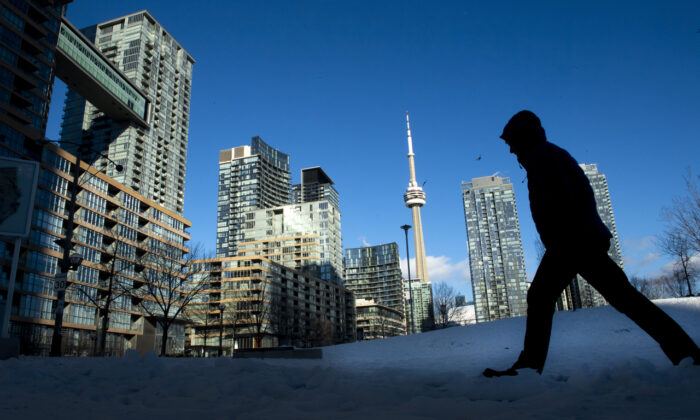 A pedestrian makes his way through condo towers in Toronto, Ontario, on Jan. 28, 2021. (Frank Gunn/The Canadian Press)
