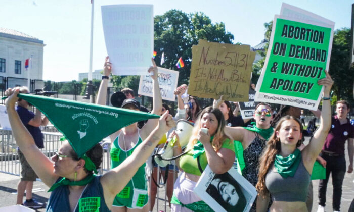Pro-abortion protesters with Rise Up 4 Abortion Rights wear green as they protest outside the U.S. Supreme Court in Washington on June 15, 2022. (Jackson Elliott/The Epoch Times)
