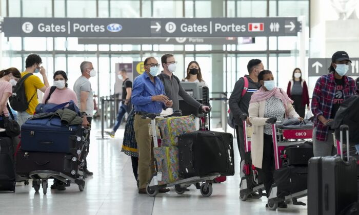 People wait in line to check in at Pearson International Airport in Toronto on May 12, 2022. (Nathan Denette/The Canadian Press)