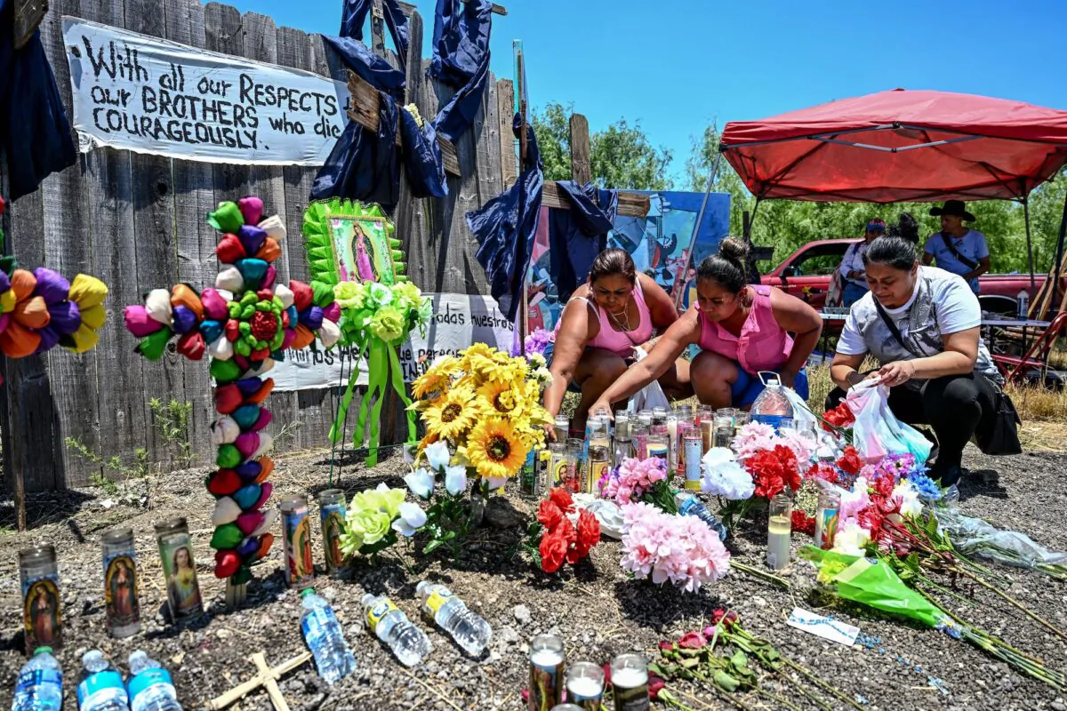 People place flowers and candles at a makeshift memorial where a tractor-trailer was discovered with deceased illegal immigrants inside, near San Antonio, Texas, on June 29, 2022. (Chandan Khanna/AFP via Getty Images)
