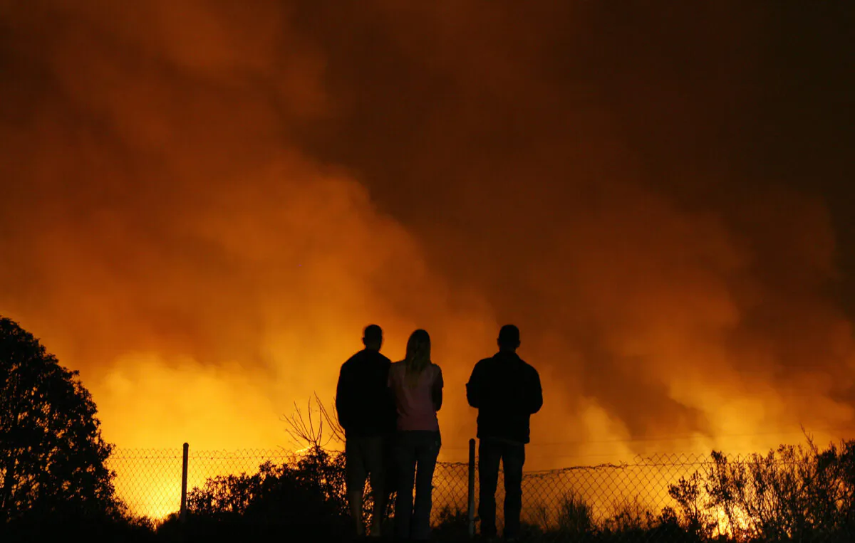 People watch a fire close to Highway 5 near Oceanside, Calif., on Oct. 24, 2007. (Gabriel Bouys/AFP via Getty Images)