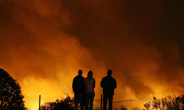 People watch a fire close to Highway 5 near Oceanside, Calif., on Oct. 24, 2007. (Gabriel Bouys/AFP via Getty Images)