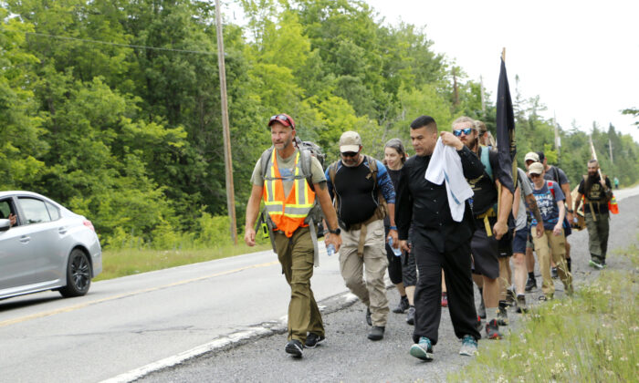 Veteran James Topp (L) and his group walk on a rural road west of Ottawa, as the driver of a car waves, on June 29, 2022. On Topp's left is epidemiologist Dr. Paul Alexander. (Noé Chartier/The Epoch Times)