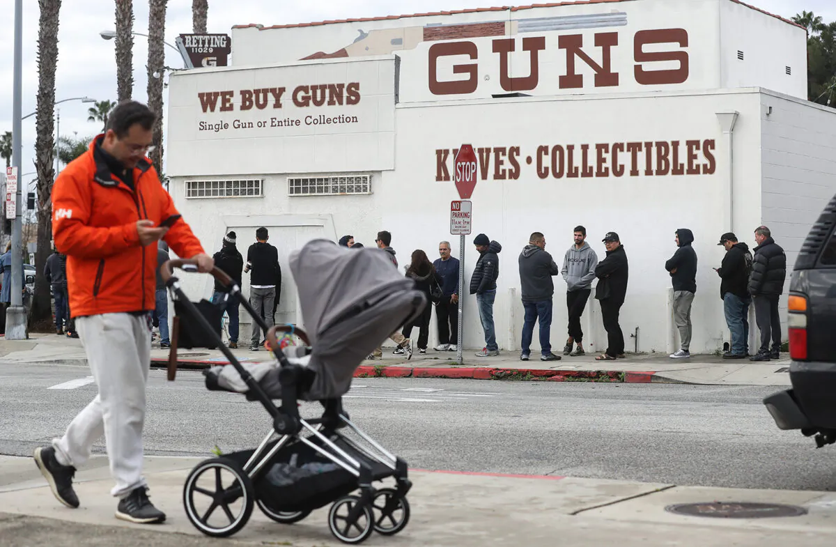 A man walks with a stroller as people stand in line outside the Martin B. Retting, Inc. guns store , in Culver City, Calif., on March 15, 2020. (Mario Tama/Getty Images/TNS)