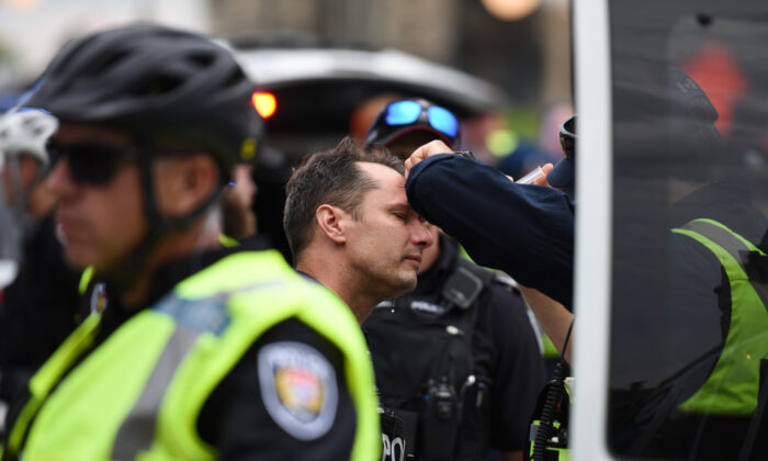 A police officer receives treatment after four people were arrested in a demonstration in downtown Ottawa on June 30, 2022. (The Canadian Press/Spencer Colby)
