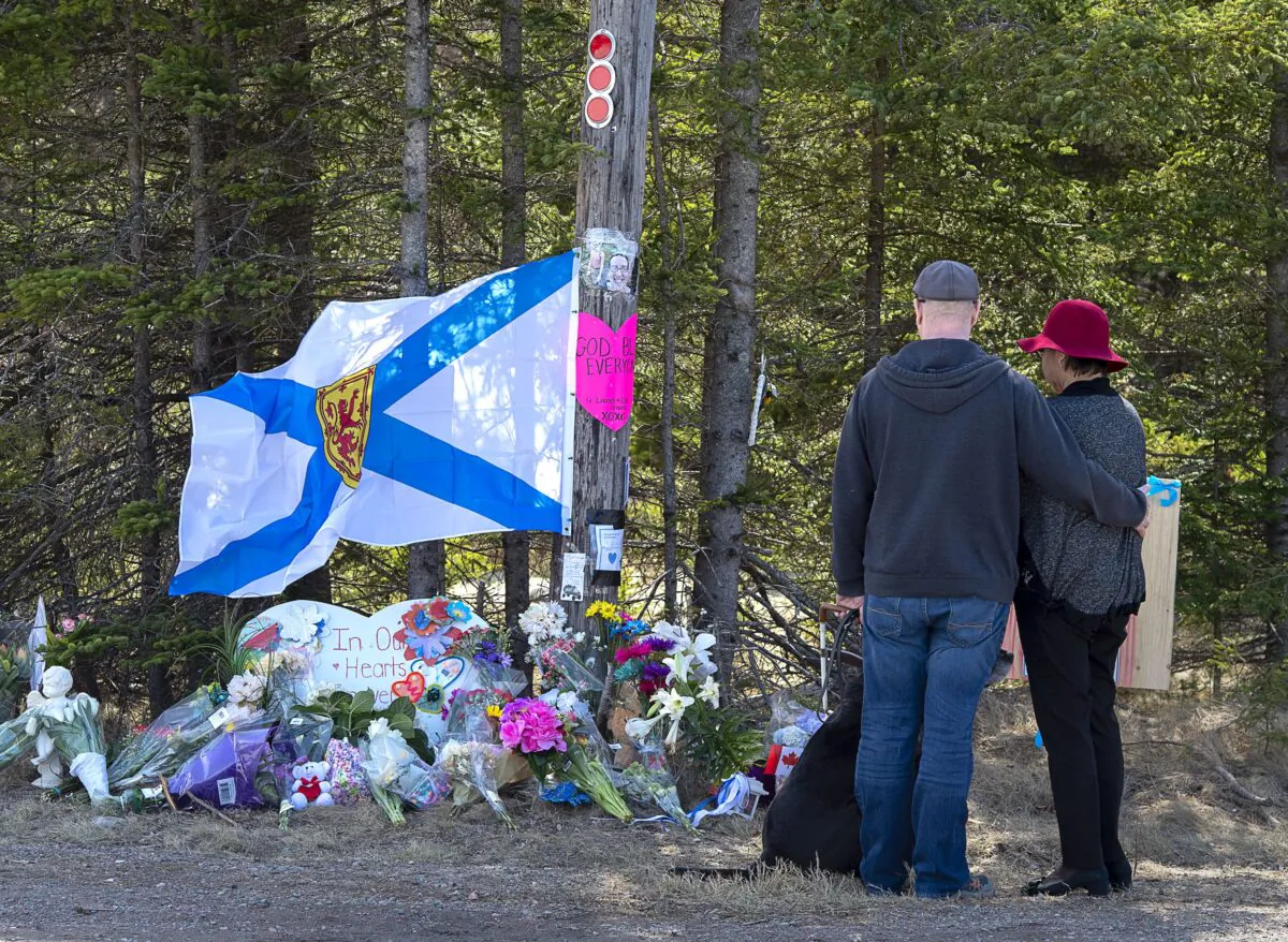A couple pay their respects at a memorial in Portapique, N.S., on April 22, 2020, for the 22 people killed in a mass shooting after a gunman went on a murder rampage in Portapique and several other Nova Scotia communities. (The Canadian Press/Andrew Vaughan)