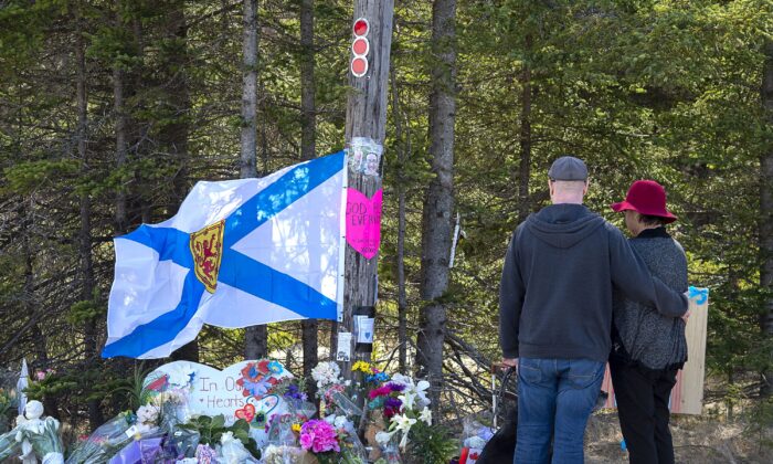 A couple pay their respects at a memorial in Portapique, N.S., on April 22, 2020, for the 22 people killed in a mass shooting after a gunman went on a murder rampage in Portapique and several other Nova Scotia communities. (The Canadian Press/Andrew Vaughan)
