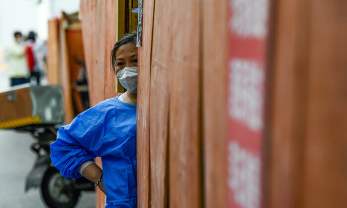 A community volunteer stands behind the fence in a residential area under a COVID-19 lockdown in Shanghai's Huangpu district on June 22, 2022. (Liu Jin/AFP via Getty Images)