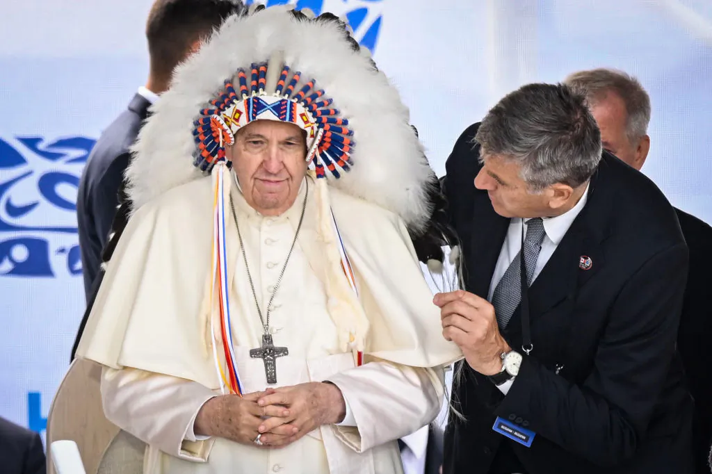 Pope Francis wears a headdress presented to him by Indigenous leaders during a meeting at Muskwa Park in Maskwacis, Alberta, Canada, on July 25, 2022. (Patrick T. Fallon/AFP via Getty Images)