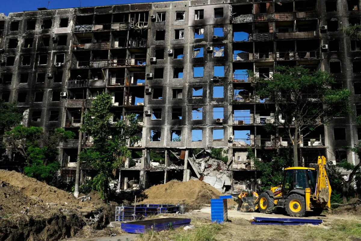 Workers get ready to dig in front of a destroyed building in the city of Mariupol on July 1, 2022. (Stringer/AFP via Getty Images)