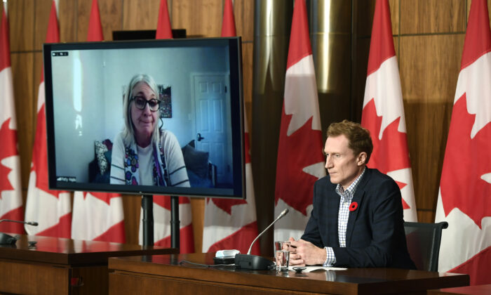 Minister of Crown-Indigenous Relations Marc Miller (R) listens as Minister of Indigenous Services Patty Hajdu, appearing via video conference, speaks during a news conference regarding the order from the Canadian Human Rights Tribunal to compensate Indigenous children and their families, in Ottawa on Oct. 29, 2021. (Justin Tang/The Canadian Press)