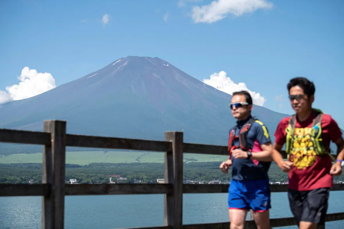 Two men jogging near the village of Yamanakako in Yamanashi prefecture, Japan,  as Mount Fuji is seen in the background, on July 19, 2021. (Charly Triballeau/AFP via Getty Images)