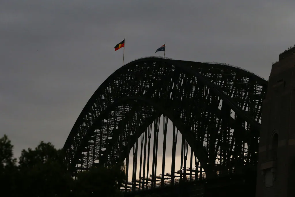 The Aboriginal flag is seen alongside the Australian flag on top of the Harbour Bridge in Sydney, Australia on January 26, 2022. (Photo by Lisa Maree Williams/Getty Images)