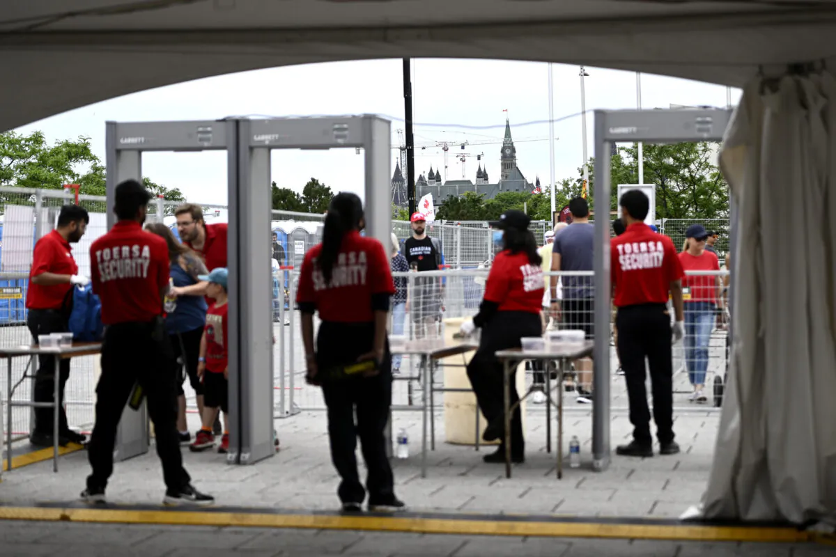 Parliament Hill is seen beyond a security screening area for people arriving for Canada Day celebrations at Lebreton Flats in Ottawa on July 1, 2022. (The Canadian Press/Justin Tang)