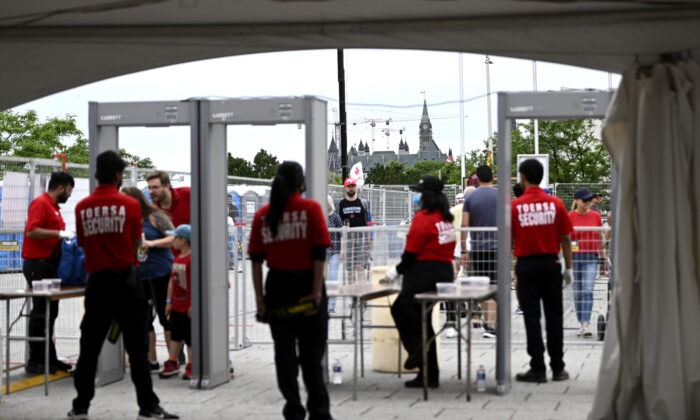 Parliament Hill is seen beyond a security screening area for people arriving for Canada Day celebrations at Lebreton Flats in Ottawa on July 1, 2022. (The Canadian Press/Justin Tang)