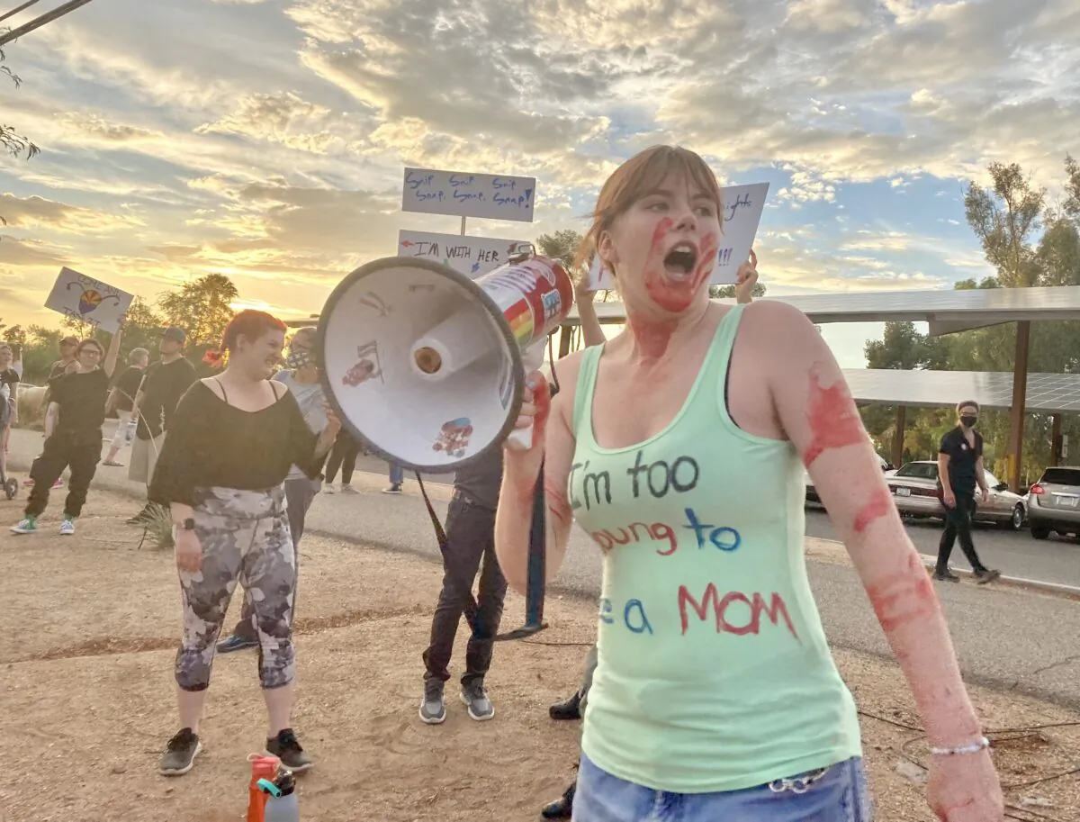 An unidentified protester covered in fake blood shouts into a bullhorn at a Women's March in support of abortion and promoted by the Pima County Democratic Party in Tucson, Ariz., on July 4. (Allan Stein/The Epoch Times)