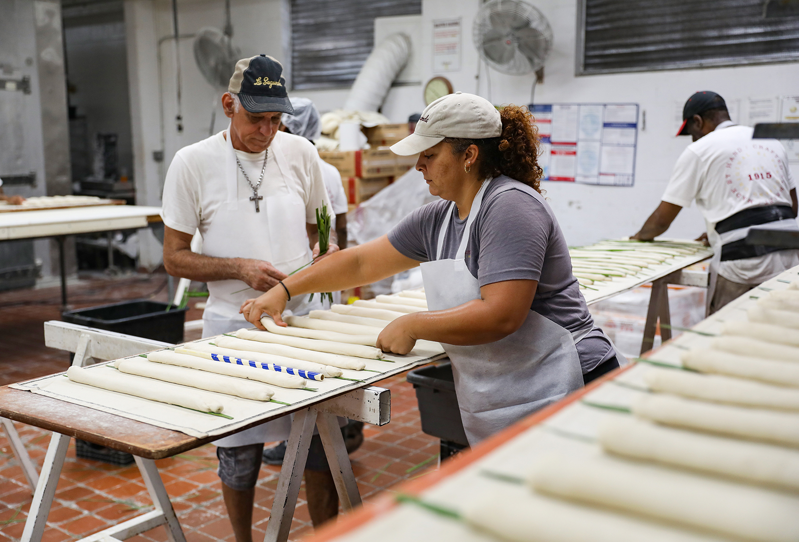 Yovanni Perdomo (36), middle, and Carlos Cabota (56), left, of Tampa place palmetto leaves on loaves and flip them at La Segunda Central Bakery in Ybor City. 