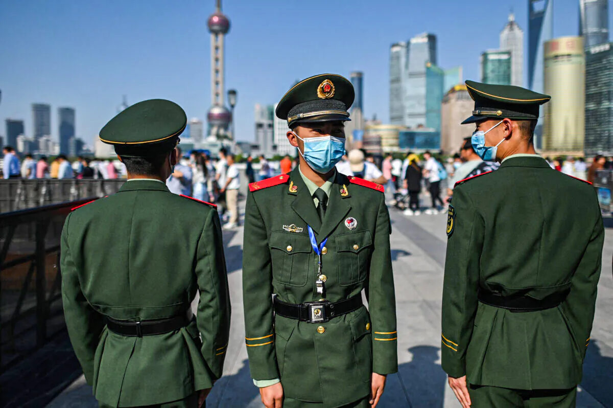 Chinese paramilitary policemen watch as people visit a promenade on the Bund along the Huangpu River in Shanghai on May 1, 2021. (Hector Retamal/AFP via Getty Images)