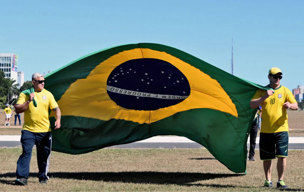 Supporters of Brazilian President Jair Bolsonaro carry a national flag as they head to the National Congress building in Brasilia, Brazil, on May 1, 2022. (Evaristo Sa/AFP via Getty Images)