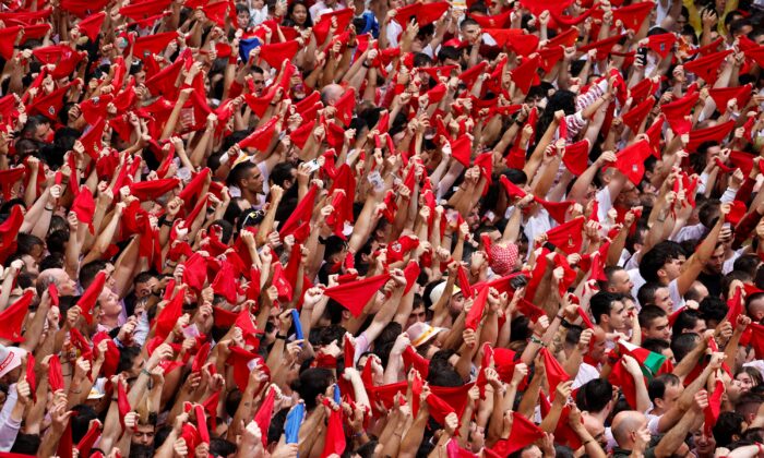 Revelers hold up traditional red scarves during the opening of the San Fermin festival in Pamplona, Spain, on July 6, 2022. (Vincent West/Reuters)