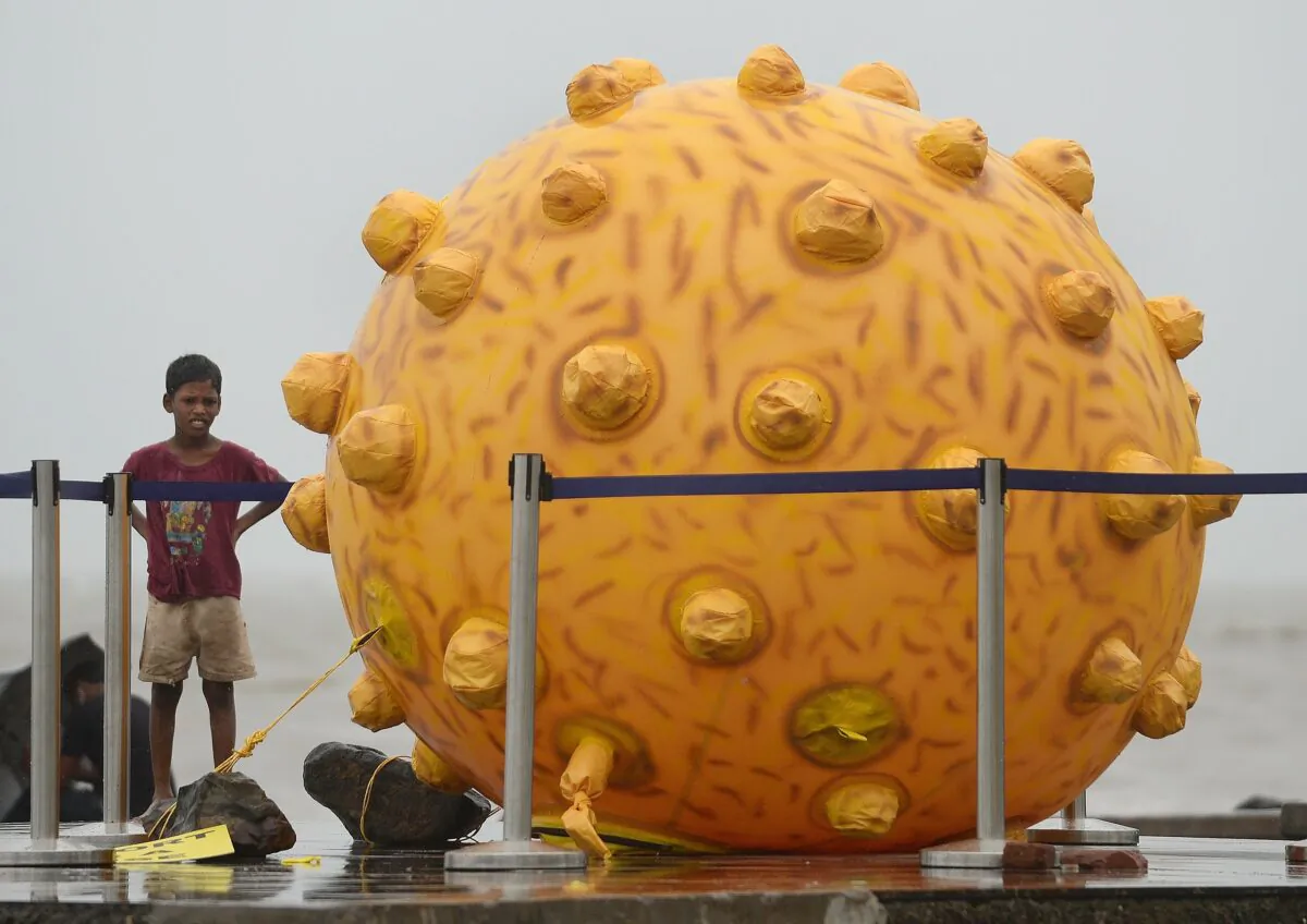 An Indian boy stands near a replica of the Hepatitis virus, a part of an awareness event in Mumbai on July 28, 2014. (Punit Paranjpe/AFP via Getty Images)
