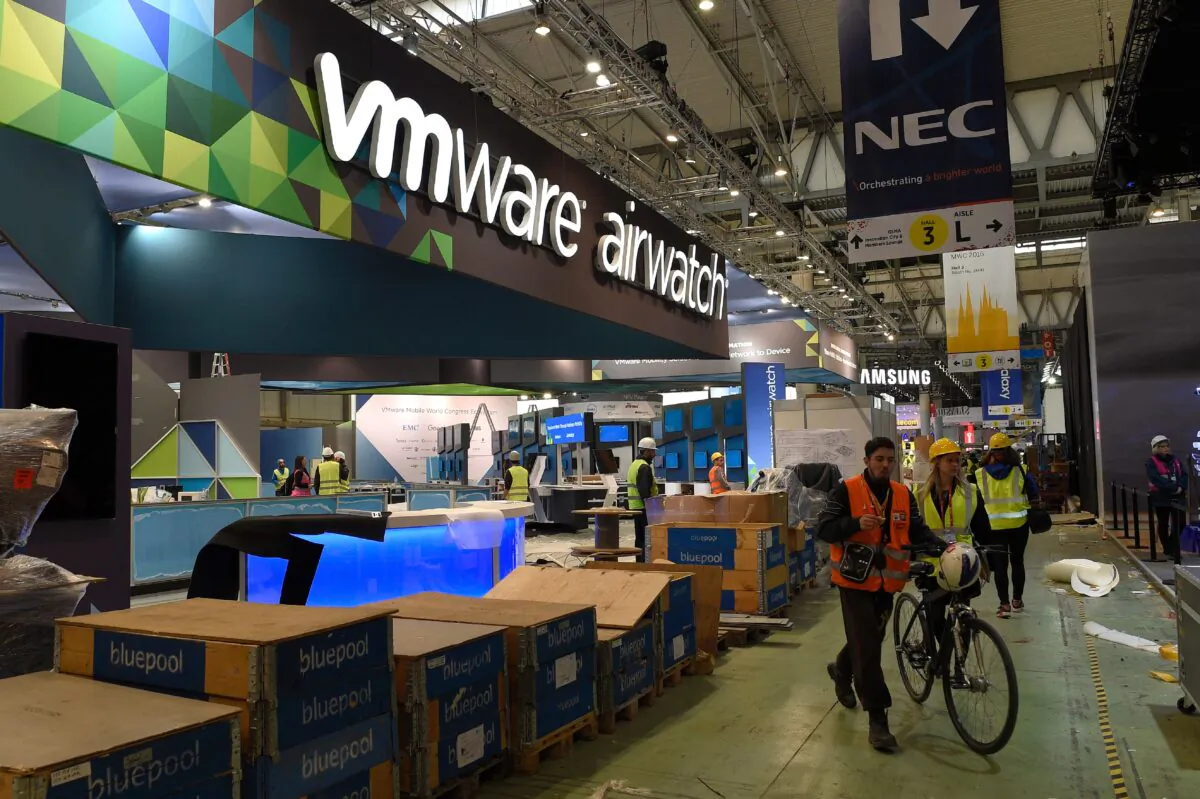 Some people walk past the VMware company stand as facilities for the Mobile World Congress in Barcelona are set up on Feb. 20, 2016. (Lluis Gene/AFP via Getty Images)