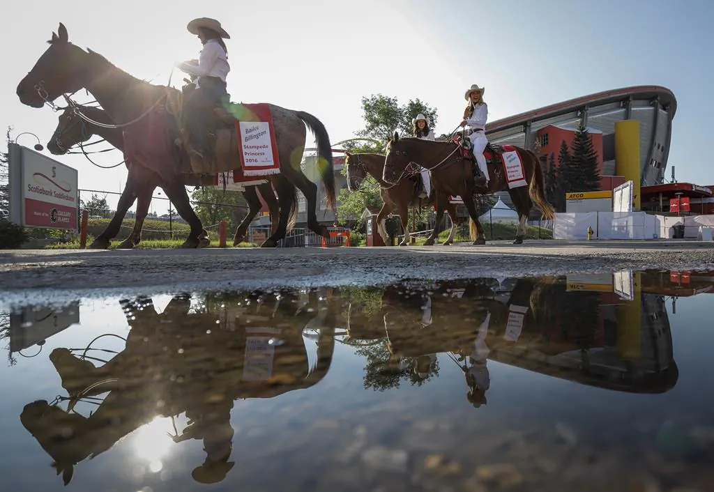 Stampede princesses ride past the Saddledome during the Calgary Stampede parade in Calgary on July 9, 2021. (Jeff McIntosh/The Canadian Press)