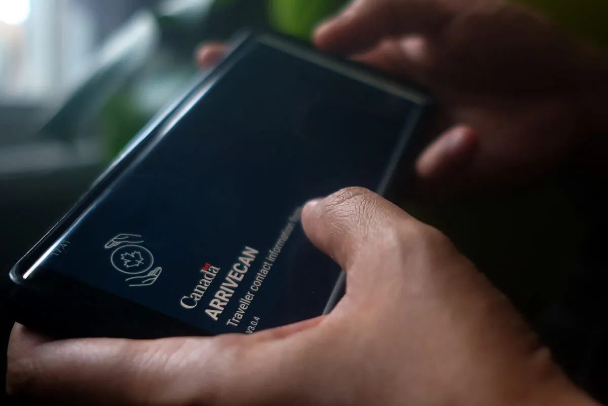 A person holds a smartphone showing the ArriveCan app, which required people to upload their COVID-19 vaccination status to be able to enter Canada during the pandemic. (Giordano Ciampini/The Canadian Press)