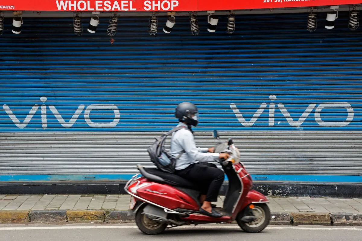 A scooterist rides past an advertisement of Chinese mobile phone maker Vivo, painted on a shuttered shop of a market in Mumbai on July 31, 2020. (Indranil Mukherjee/AFP via Getty Images)