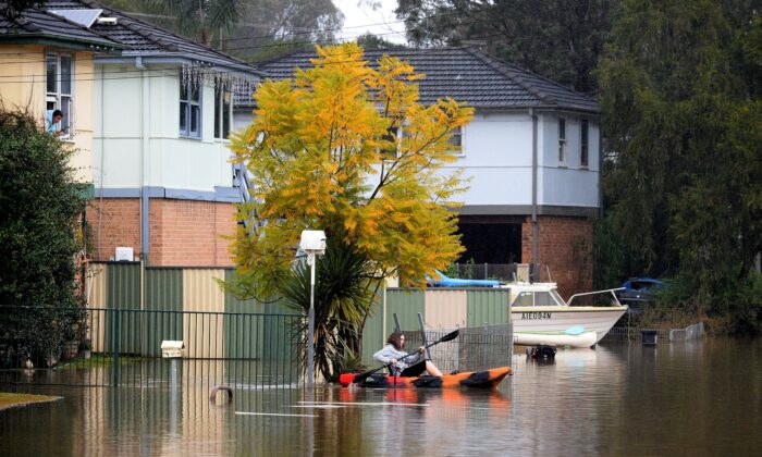 A resident paddles a kayak to commute in the Sydney, Australia, on July 6, 2022. - Thousands of Australians were ordered to evacuate their homes in Sydney as torrential rain battered the country's largest city and floodwaters inundated its outskirts. (Muhammad Farooq/AFP via Getty Images)
